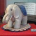 Grauer Filzelefant von Steiff mit blauer Decke auf dem Rücken als Nadelkissen