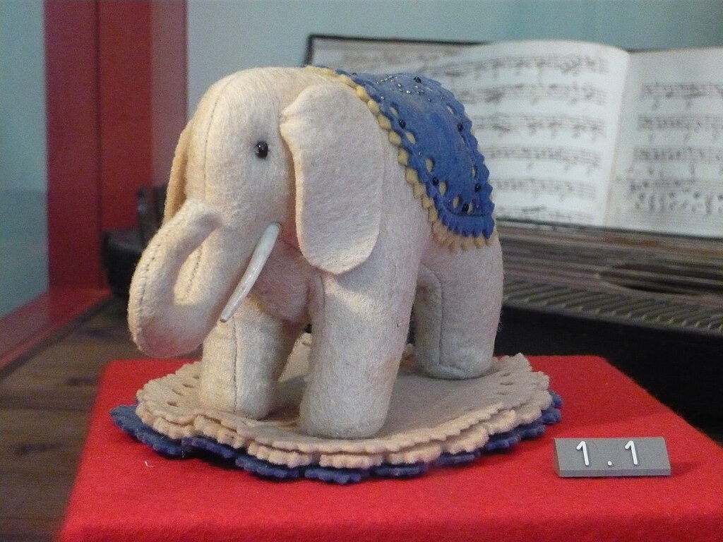 Grauer Filzelefant von Steiff mit blauer Decke auf dem Rücken als Nadelkissen