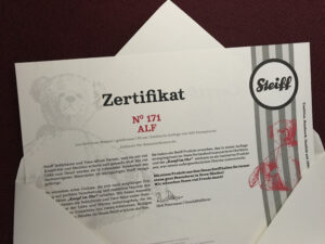 Luxusplüsch.Alf Steiff Zertifikat mit Nummer 171 in roter Schrift und Steiff Logo im offenen Umschlag