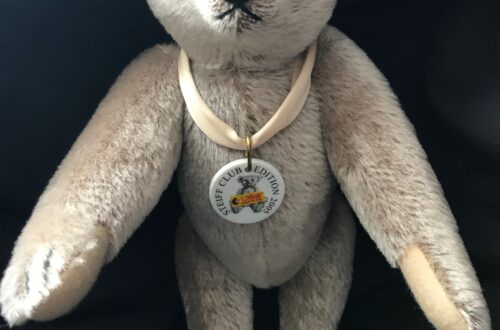 Luxusplüsch. Richard Steiff Teddy in grau, hellbeige Bärenpfoten, 30 cm groß mit hellbeiger Seidenschleife und Porzellanmarke um den Hals
