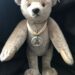 Luxusplüsch. Richard Steiff Teddy in grau, hellbeige Bärenpfoten, 30 cm groß mit hellbeiger Seidenschleife und Porzellanmarke um den Hals