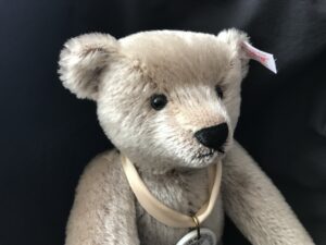 Luxusplüsch.Richard Steiff Teddy in grau, Kopf mit hellbeiger Seidenschleife und Porzellanmarke um den Hals