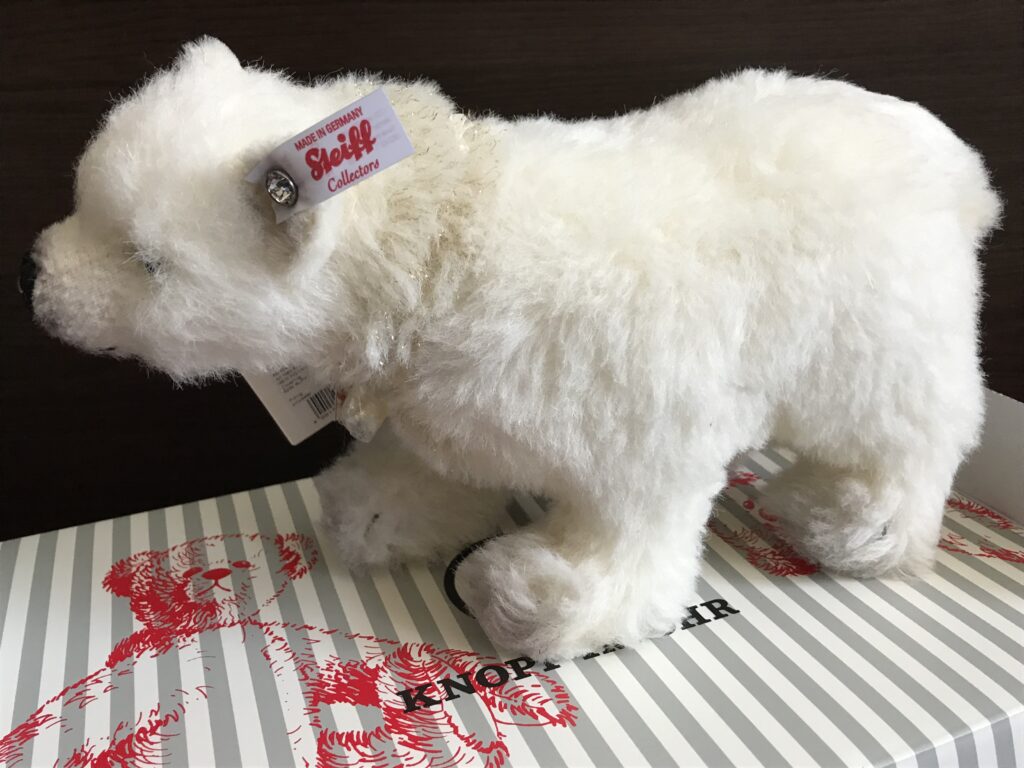 Luxusplüsch. Steiff Winterpolarbär mit weißer Fahne und roter Schrift im linken Ohr auf Karton stehend